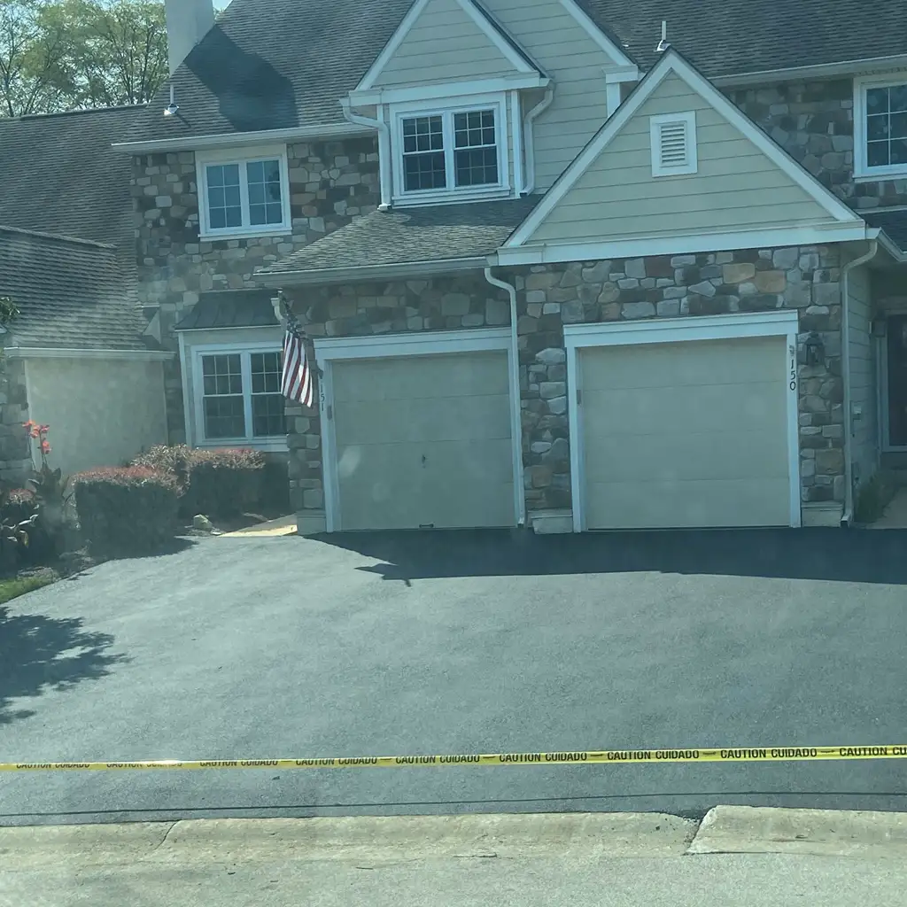 Freshly paved residential asphalt driveway in front of a stone house in Downingtown, Pennsylvania.